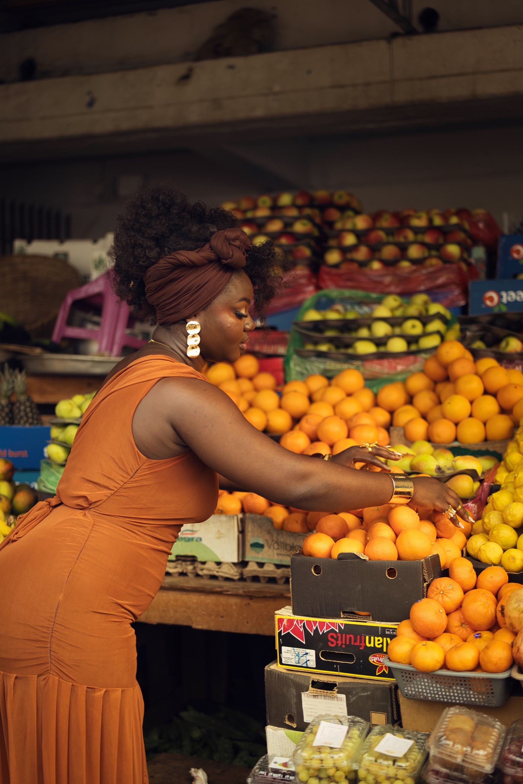 A confident African market entrepreneur serving customers among fresh produce.