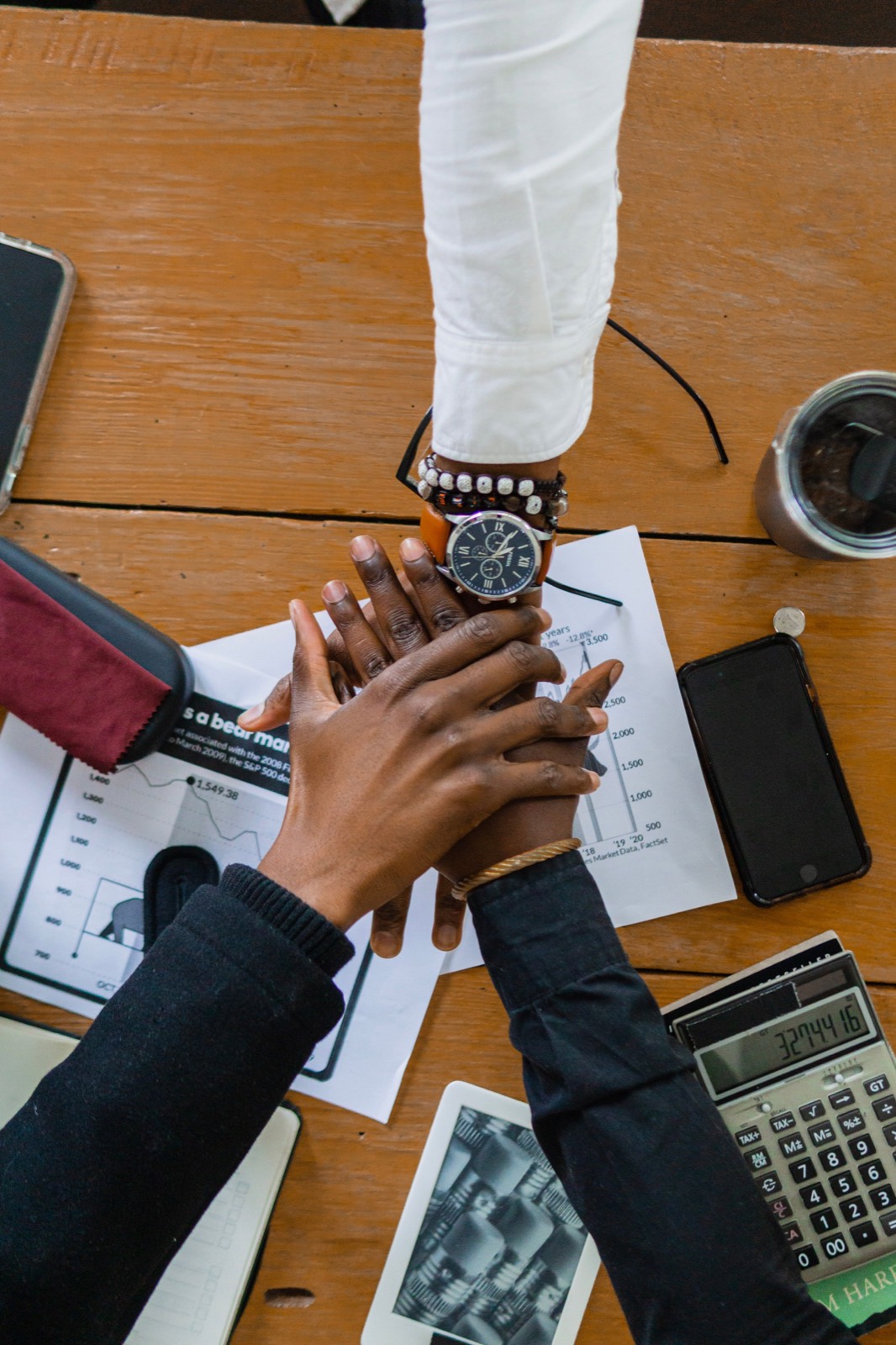 Business records, charts, a calculator and hands in discussion.