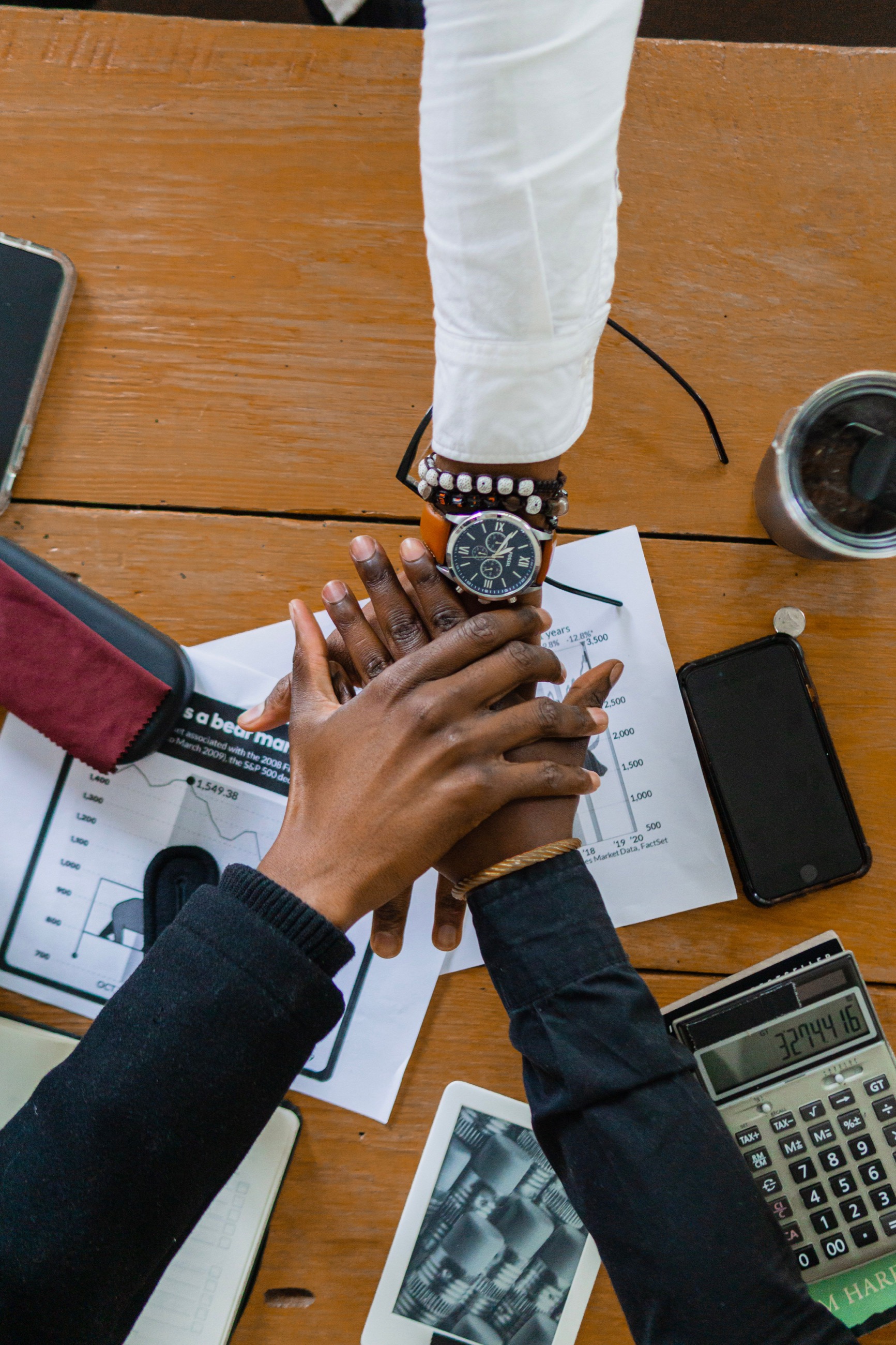 Business records, charts, a calculator and hands in discussion.